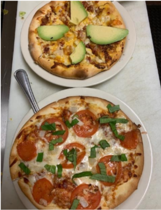 Two freshly made pizza on white plates